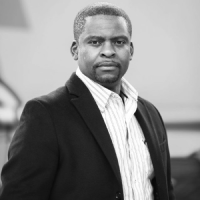 Black and white professional headshot of a man in a blazer and collared shirt, symbolizing engineering leadership